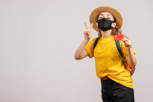旅游正面图戴黑面具的年轻女子手持制牌胜利标志旅行者人持有
