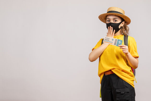 年轻女子正面图戴着黑色面具的年轻女子拿着旅行票旅游运动员旅游