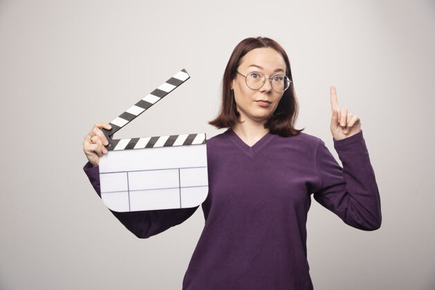 女性一位年轻的女士正在用一张高质量的白色照片播放电影录像带磁带人类姿势