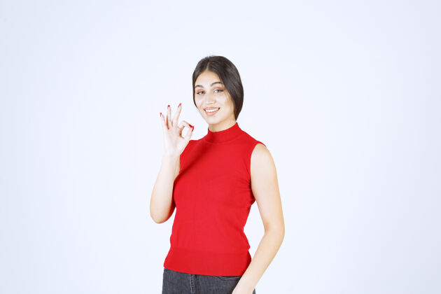 协议穿红衬衫的女孩显示出积极的手势喜欢人满意