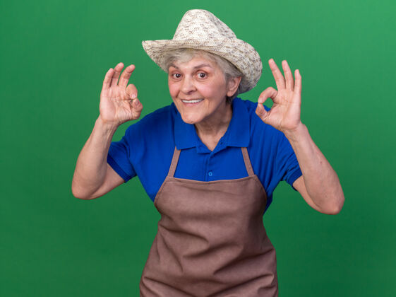 女性给人印象深刻的上了年纪的女园丁戴着园艺帽用两只手示意ok标志印象手Ok