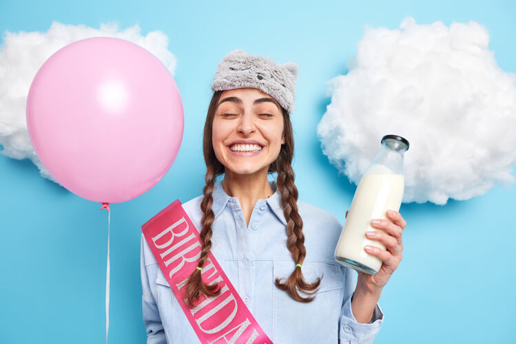 模特头戴睡眠面罩的女士手持玻璃奶瓶和气球在蓝色的衬托下享受温馨的国内氛围蒙着眼睛牛奶瓶子