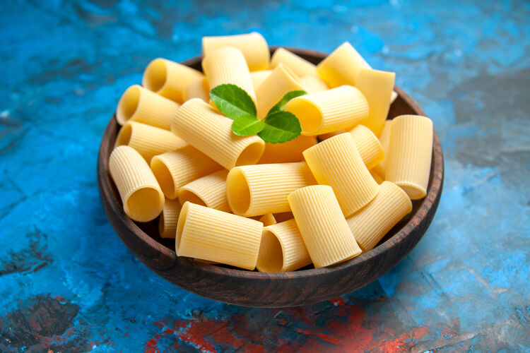 糖晚餐准备的侧视图 蓝色背景的棕色锅中有绿色的意大利面食品健康糖果