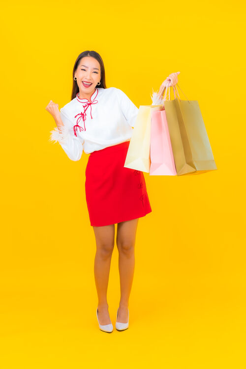 消费主义一位年轻漂亮的亚洲女士 手拿购物袋 信用卡 黄色借记互联网客户