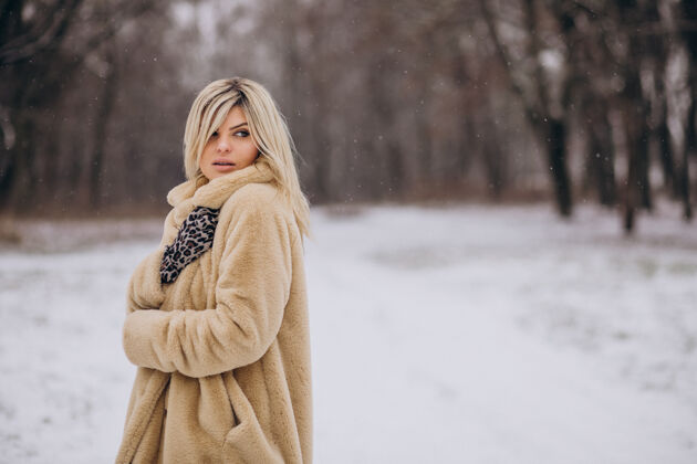 寒冷穿着冬衣的美女在满是雪的公园里散步降雪波西米亚女孩