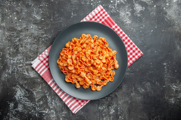 盘子上图：美味的意大利面 放在黑色的盘子里 在黑色的背景下 红色的条状毛巾上晚餐炊具背景