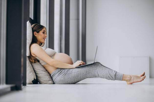 产前女人在家用电脑网络靠窗腹部