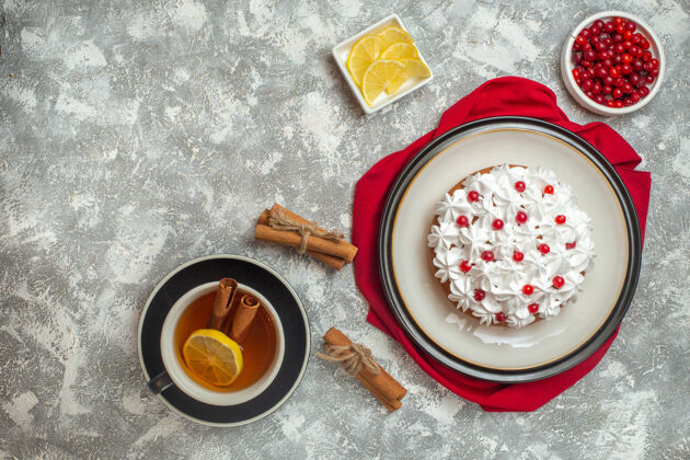 笔记本上图：红色毛巾上点缀着水果的奶油蛋糕和一杯红茶和肉桂酸橙柠檬肉桂醋栗