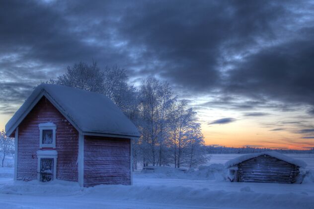田野日落时 田野里的小木屋被雪覆盖了日落小屋顶