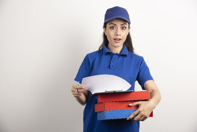 工作年轻的女信使拿着一纸板披萨和剪贴板剪贴板盒子披萨