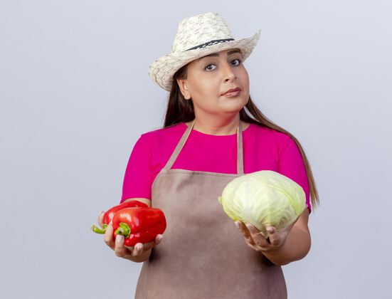 花园围裙戴帽子的中年园丁 手里拿着甜椒和卷心菜 看上去很自信帽子围裙卷心菜