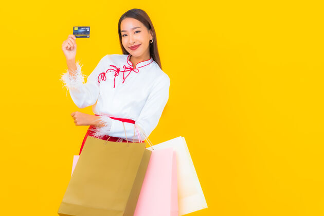 购物一位年轻漂亮的亚洲女士 手拿购物袋 信用卡 黄色购物者泰国客户