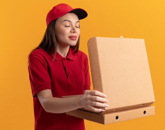 假装穿着制服的漂亮送货员拿着披萨盒假装闻漂亮拿着橘子