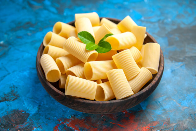 糖晚餐准备的侧视图 蓝色背景的棕色锅中有绿色的意大利面食品健康糖果