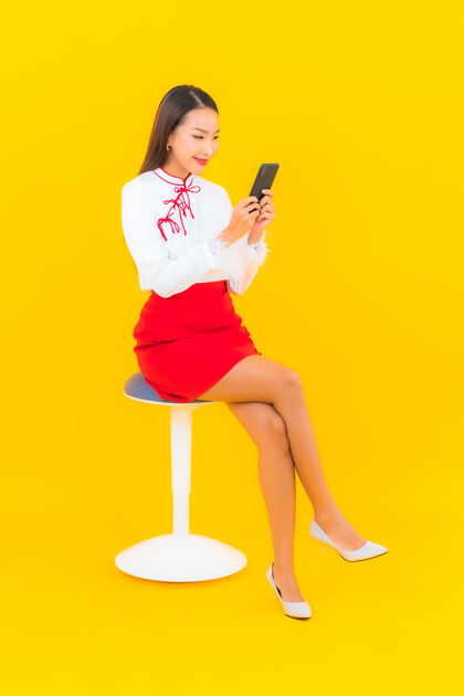 休闲用黄色的智能手机描绘美丽的亚洲年轻女子在线成人电话