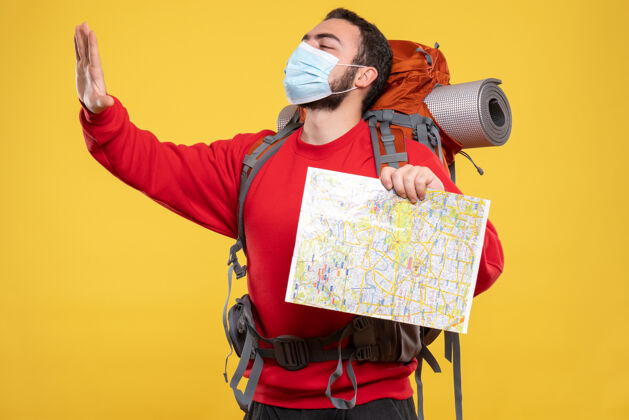 人顶视图年轻自豪的旅行者家伙戴着医疗面具与背包举行黄色地图相机成人地图