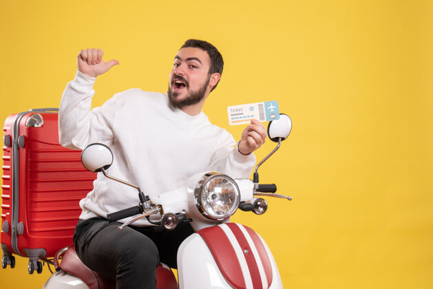 肌肉旅行的概念与微笑的男子坐在摩托车上 手提箱上显示黄色车票票运动员人