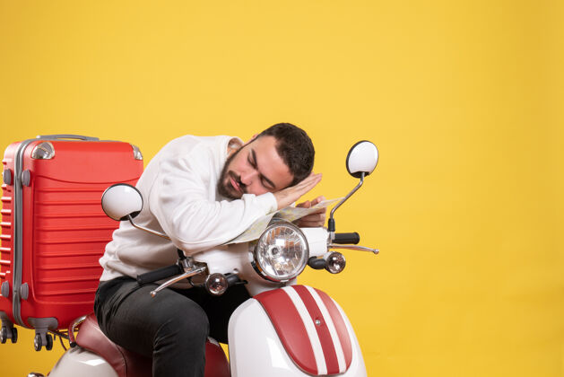 运动旅行的概念与昏昏欲睡的家伙坐在摩托车上的手提箱上的黄色旅行人足球