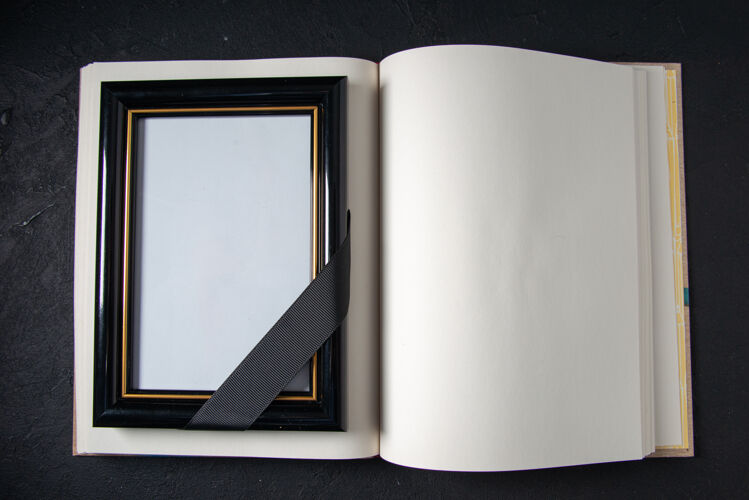葬礼打开的书的顶视图 深色墙上有相框空打开的书黑暗