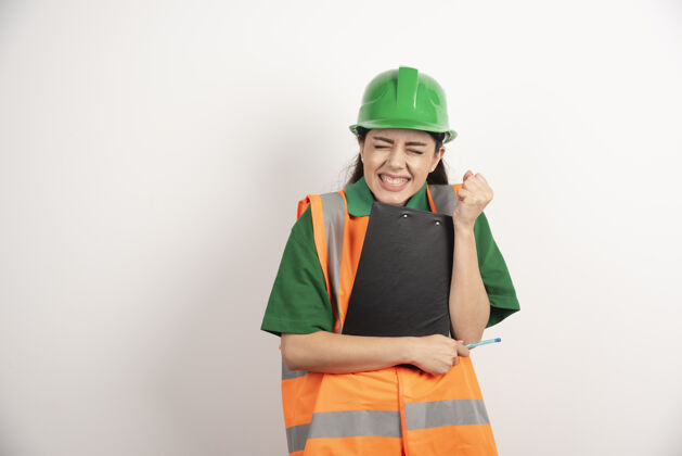 地产愤怒的女施工员戴着绿色头盔站在剪贴板上高质量的照片女商人承包商工程师