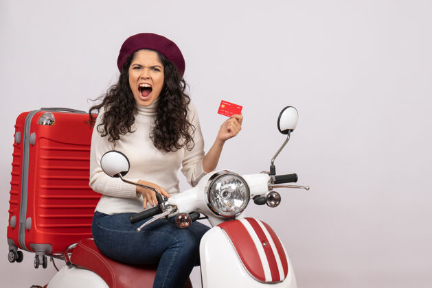 人正面图骑自行车的年轻女性手持红色银行卡在白色背景上城市彩色道路车辆摩托车超速度假赚钱金钱车辆摩托车