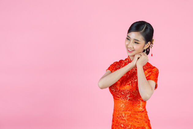 衣服美丽的亚洲女人快乐的微笑 在中国新年的粉红色背景上向你展示一些东西空白东方人年
