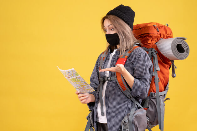肖像带着黑色面具和背包的旅行女孩在看地图女士人女孩旅行者