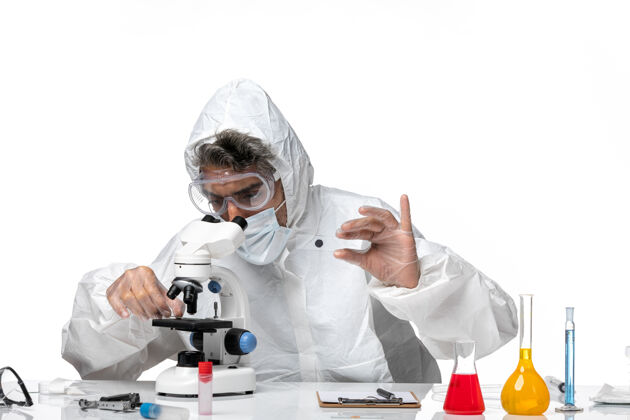 显微镜男医生穿着防护服 带无菌口罩 用显微镜观察浅白色医学视图医生