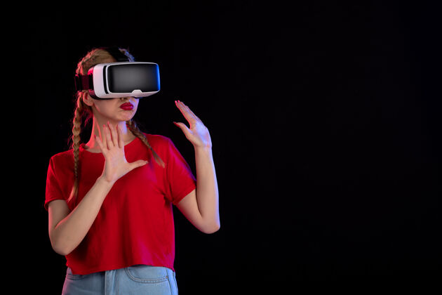 成人年轻女性在黑暗的墙上玩虚拟现实的前视图虚拟现实正面游戏