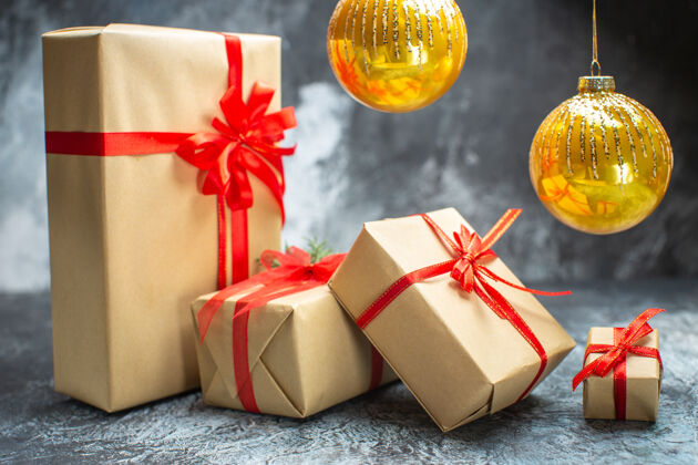 庆祝前视图圣诞礼物与红色蝴蝶结绑在一个浅黑色新年假期圣诞礼物照片前面新的礼物