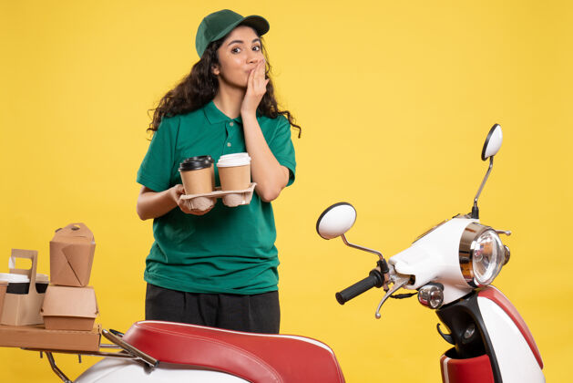 女信使正面图身着绿色制服的女快递员在黄色背景上涂咖啡工作送货工作食品服务人员美女成人咖啡