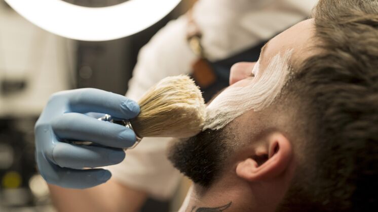 男性理发师用剃须膏勾勒男顾客的胡须轮廓乳胶手套理发师专业