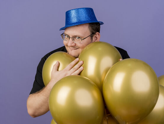 太空兴奋的成年斯拉夫人戴着眼镜 戴着蓝色派对帽 手里拿着氦气球气球眼镜穿