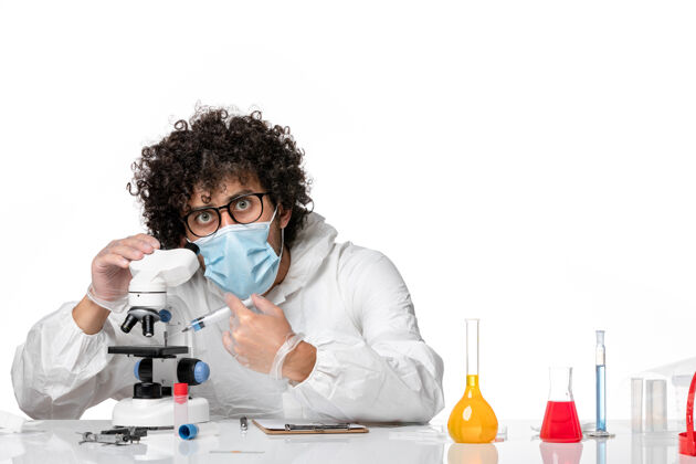 大流行男医生穿着防护服 戴着口罩 用显微镜在白色上工作专业口罩男医生