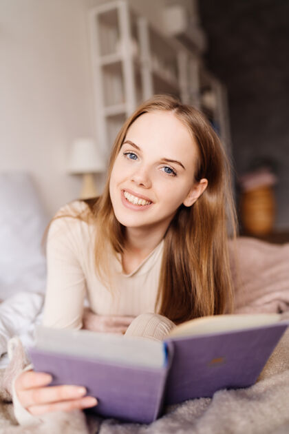 舒适年轻漂亮的女人在家里的床上享受着最喜欢的书单身快乐人