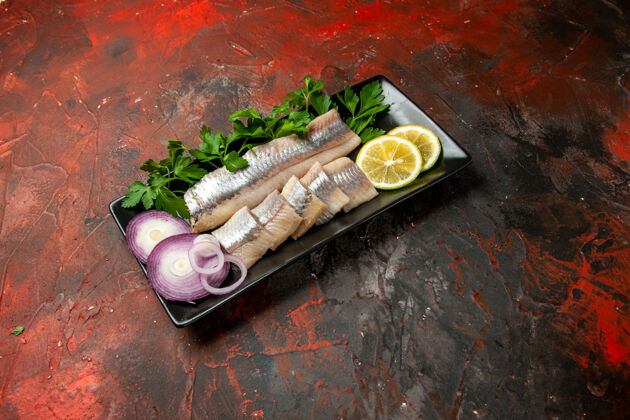 盘子前视图新鲜鱼片与绿色和洋葱内黑锅上的黑色小吃肉色餐海鲜正餐肉午餐