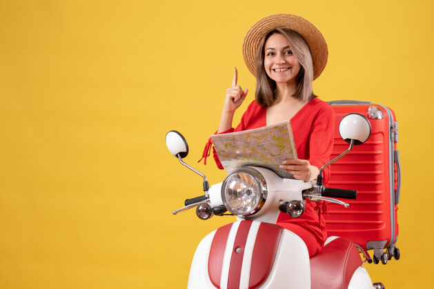 红色骑着轻便摩托车的漂亮女孩 手拿红色手提箱 手指着地图成人剪影手指