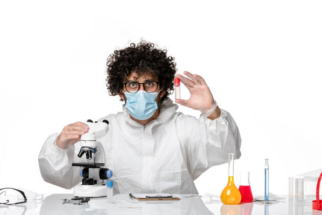 药品男医生穿着防护服 戴着口罩 用显微镜把样本拿在白色的纸上使用医疗实验室外套