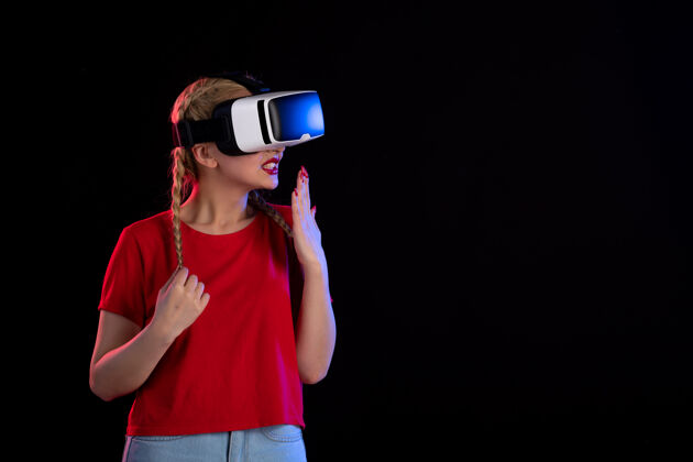 年轻女性年轻女性在黑暗的墙上玩vr的正面图虚拟现实游戏黑暗