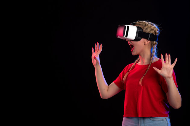 正面年轻女性在黑暗的墙上玩虚拟现实的正面图虚拟现实人物视图