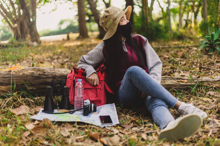 相机亚洲女游客戴着口罩坐着休息女孩森林游客