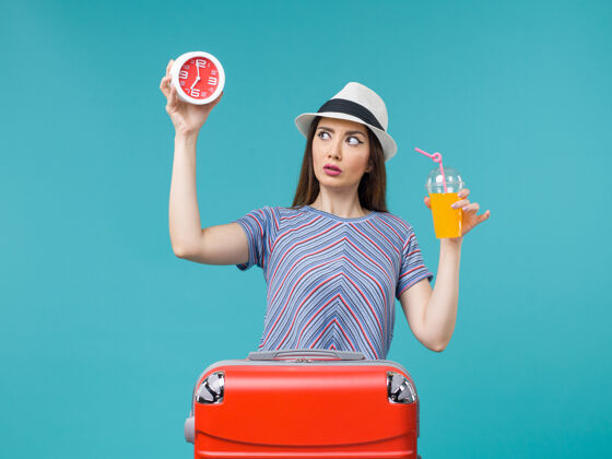 举行前景：度假中的女人拿着果汁和蓝色桌子上的钟远航度假海上旅行果汁微笑旅程
