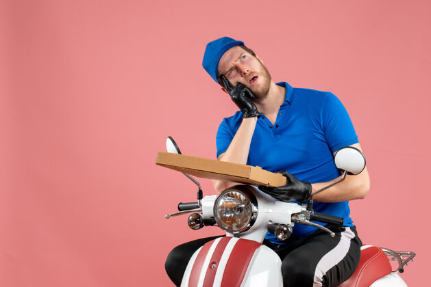 工作正面图男性信使坐在自行车上 拿着粉红色的比萨饼盒足球工人快餐