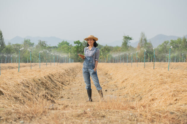 亚洲聪明的农场美丽的农民用平板电脑控制她的农场和生意 开心而微笑商业和农业概念农民或农艺师检查准备种菜的地块农场有机智能