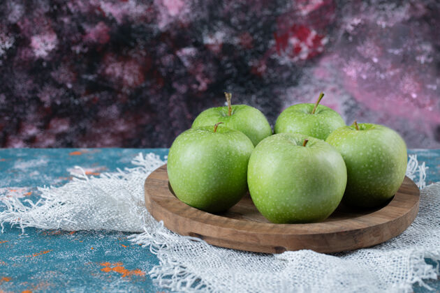美味绿色的苹果放在蓝色的木盘上产品食物板