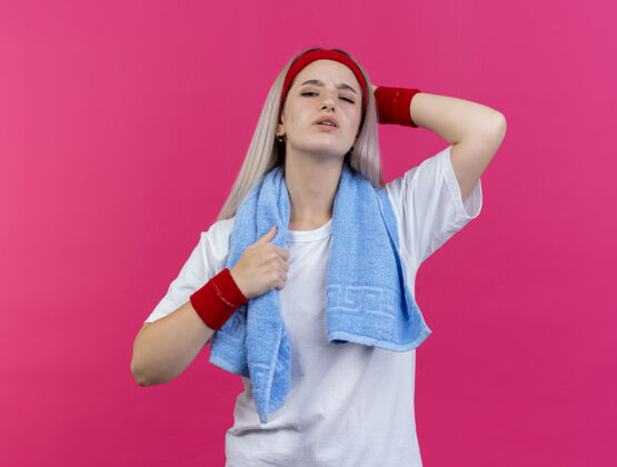 头疼痛的年轻白人运动女孩戴着背带 脖子上戴着毛巾 戴着头带和腕带 手放在脑后空间头带运动