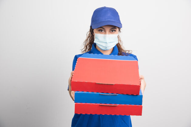 成人送比萨饼的女孩手里拿着三盒白色的医用面膜面罩送货女性