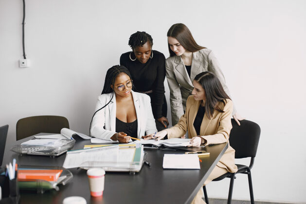 商务女性不同种族的上班族女孩坐在办公桌前一起工作 讨论商业项目专业人士员工黑色