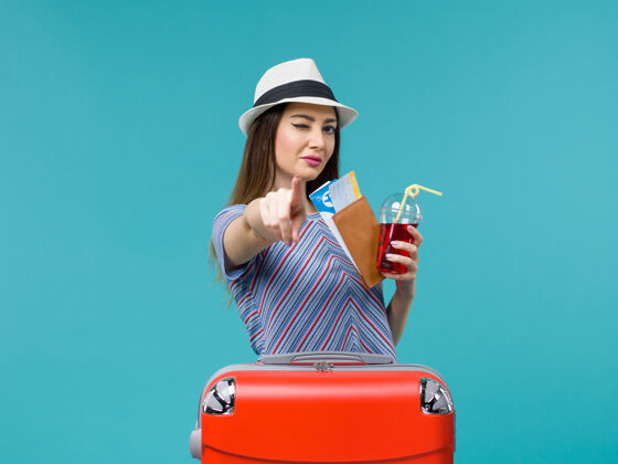 果汁前景度假中的女人拿着果汁和机票上蓝色背景的航程女海上避暑飞机美丽女成人
