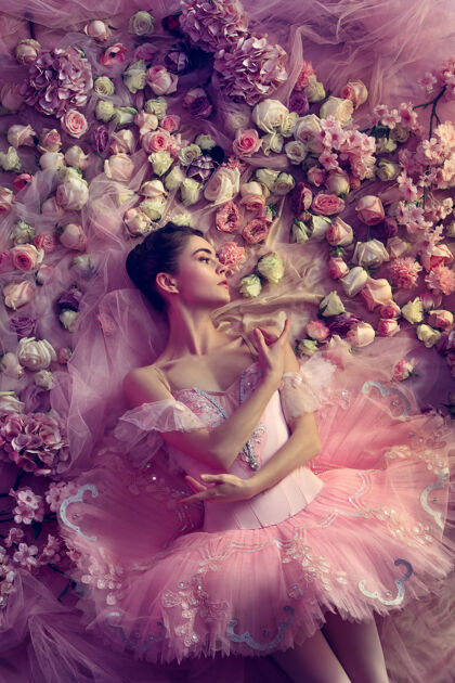 美丽俯瞰美丽的年轻女子在粉红色芭蕾舞团图图周围的鲜花芭蕾舞时尚姿势